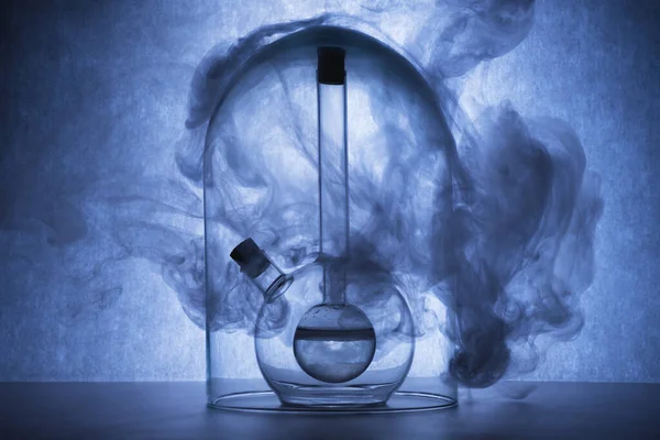 Chemical reaction in glassware on blue background. Flasks with liquid and smoke. Chemical laboratory, science concept. Creative glassware. Copy space