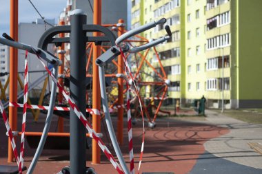 Coronavirus COVID-19 kısıtlaması. Karantina yüzünden kimse yok. Şehirdeki çocuk parkı kapalıydı. Boş park ve oyun alanı. Evinizde kalabilirsiniz. Salıncak ve slaytlarda kırmızı uyarı bandı