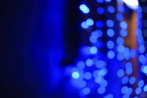 Natural blue bokeh lights abstract background. Dark blurred blue backdrop. Blurred street lights. Defocused, copy space