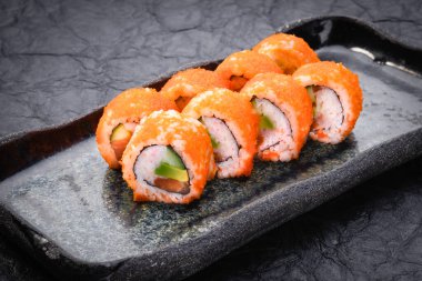 Suşi seti koyu arka planda servis edilir. Maki Roll, Philadelphia maki masago, somon, krem peynir, avokado ve karides. Çeşitli suşiler. Japon yemeği. Restoran menüsü. Yan görünüm, kapat