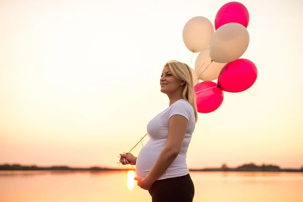 Pregnant woman holding balloons Royalty Free Stock Images