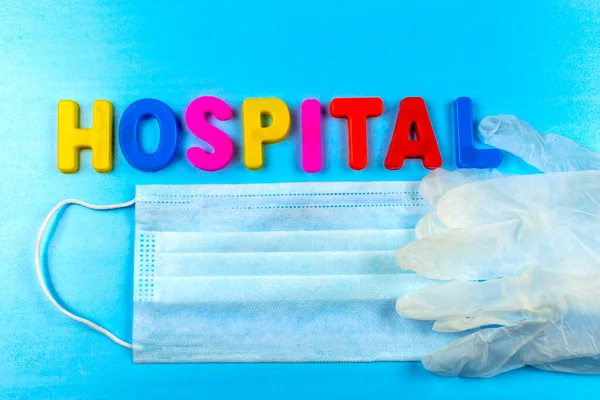Hastane kelimesi harflerden oluşur. Koronavirüs, tıbbi maske ve eldivenlerden korunma. Halka açık bir yerde korunma aracı..