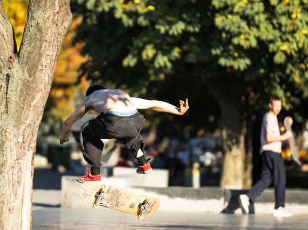 Een Jongeman Een Stadspark Maakt Een Skateboardsprong Achteraanzicht Met Wazige — Stockfoto