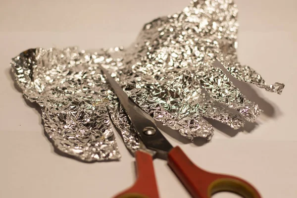 Metal food foil cut into strips and scissors. For sharpening scissors in everyday life.