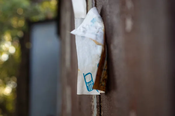 Eski metal bir garajda asılı eski bir kağıt reklamı. Bulanık arkaplanı olan yakın plan yan görünümü.