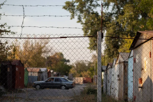 Dikenli tellerle çevrili metal araba garajları. Bulanık arkaplan.