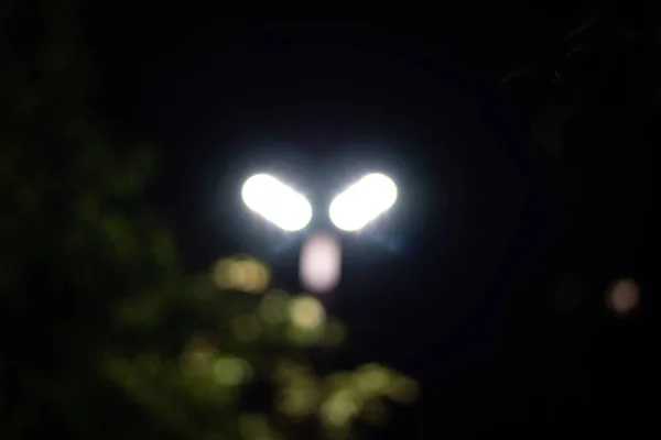 Çok katlı bir binanın akşam ışıkları ve sokak lambaları. Soyutlama.