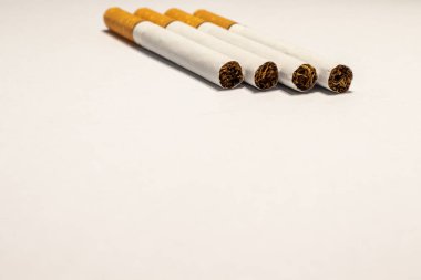 Yakınlarda turuncu filtresi olan dört sigara. Beyaz arkaplanda.