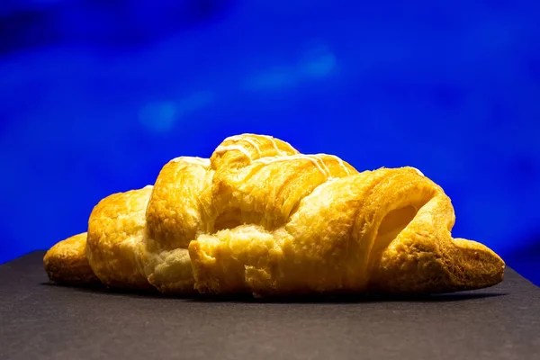 Croissant side view. Close-up on a colored background.