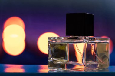 Şeffaf camdan yapılmış parfüm şişesi. Renkli bulanık arkaplanda yakın plan.