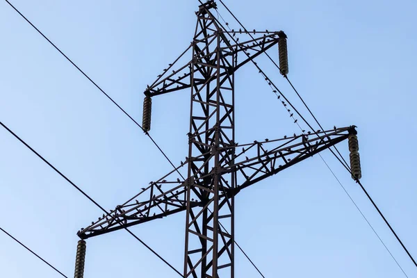 Güç iletim kulesi üzerinde mavi bir gökyüzüne karşı oturan kuşlarla dolu..