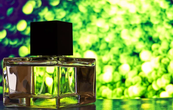 Renkli arka planda sıvı dolu şeffaf camdan yapılmış parfüm şişesi. Bulanık arkaplan ile yakın plan.