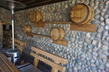 Fıçı şeklinde dolapları olan taştan yapılmış bir çardak duvarı. Tahta ve taş. Çardak tasarımı. 