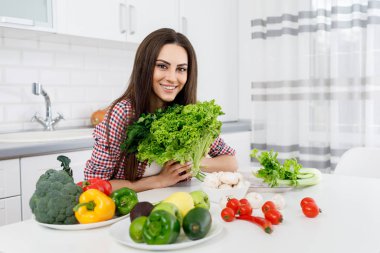 Elinde bir demet otla gülümseyen genç bayan.