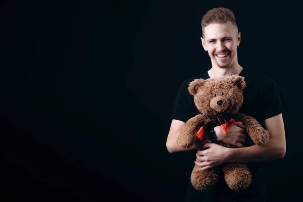 Leende stilig kille kramar en nallebjörn — Stockfoto
