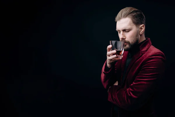 Vousatý hnědovlasý muž v sametové bundě vonící whisky — Stock fotografie
