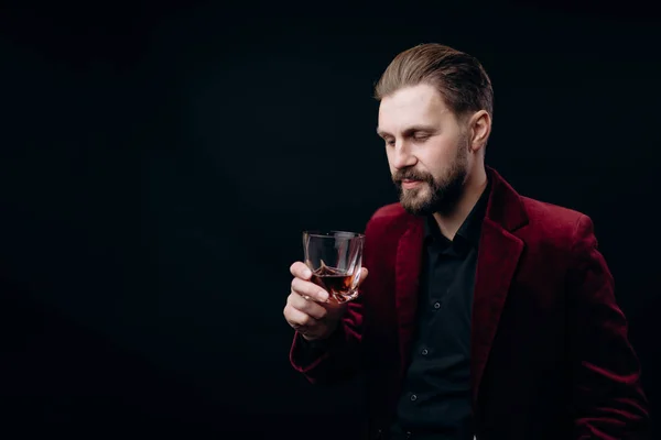 Elegante hombre con chaqueta de terciopelo mirando su bebida — Foto de Stock