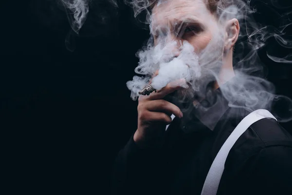 Primer plano del hombre barbudo fumando un cigarro, cara cubierta de humo — Foto de Stock