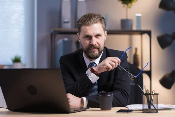 Kahverengi saçlı, sakallı ofis çalışanı bir dizüstü bilgisayarın pozu.