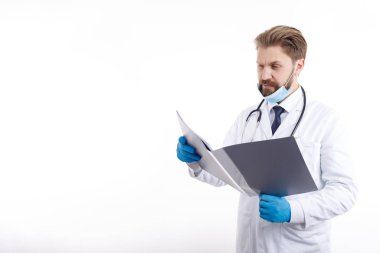 Bearded Doctor in White Scrubs Exploring Medical Documentation