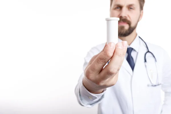Крупный план бутылки из-под лекарств, которую держит размытый доктор — стоковое фото