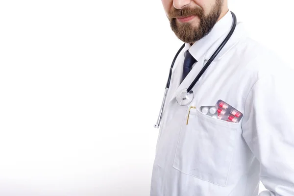 Vousatý lékař v plášti s různými pilulkami a tabletami v kapse — Stock fotografie