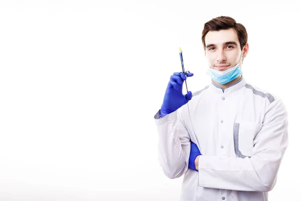 Guapo joven médico en exfoliantes blancos posando con una jeringa — Foto de Stock