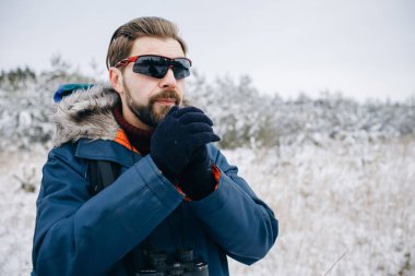 Mavi Anorak 'lı kış yürüyüşçüsü ellerini ovalıyor.