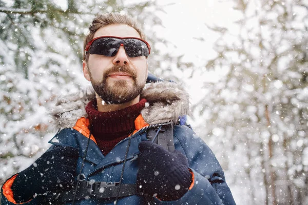 Een man die geniet van sneeuwval in het winterwoud — Stockfoto