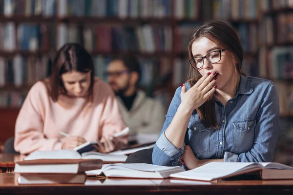 Junge Studentin fühlt sich müde in Uni-Bibliothek — Stockfoto
