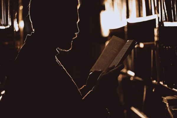 Silhouette di uomo barbuto che legge un nuovo libro in libreria — Foto Stock