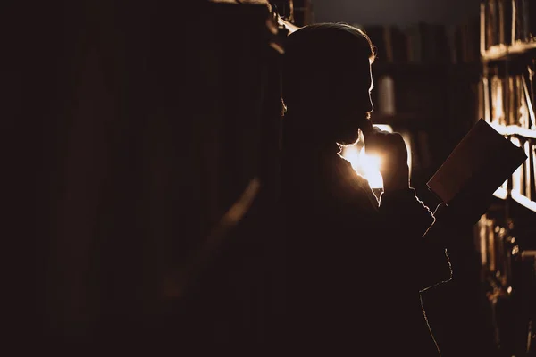 Boční pohled na vousatého čtenáře stojícího s knihou v knihovně — Stock fotografie
