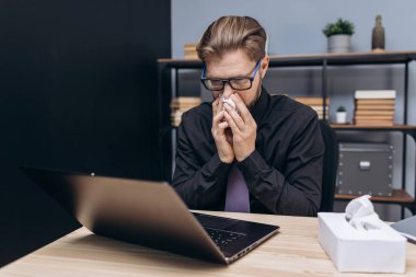 Hasta ve yorgun adam iş yerinde peçeteye burnunu siliyor.