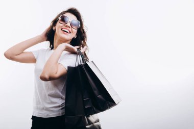 Güneş gözlüklü neşeli esmer kadın alışverişlerle poz veriyor.