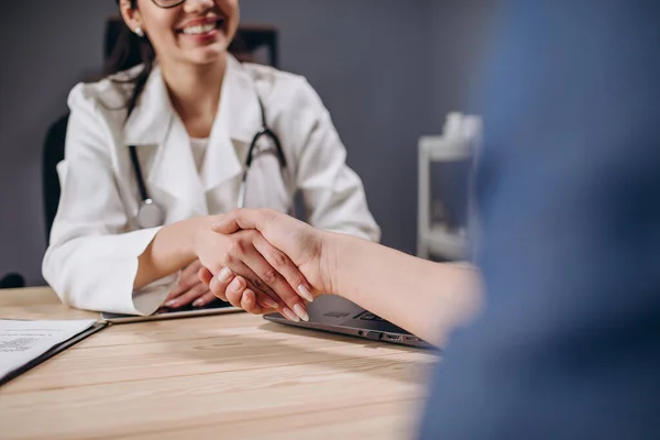 Giovane medico femminile sorridente che stringe le mani con paziente — Foto Stock