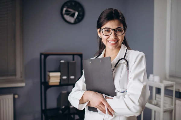 Giovane femmina medico professionale in posa in mezzo ufficio stanza — Foto Stock