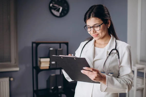 Женщина-врач делает медицинские заметки в документах — стоковое фото