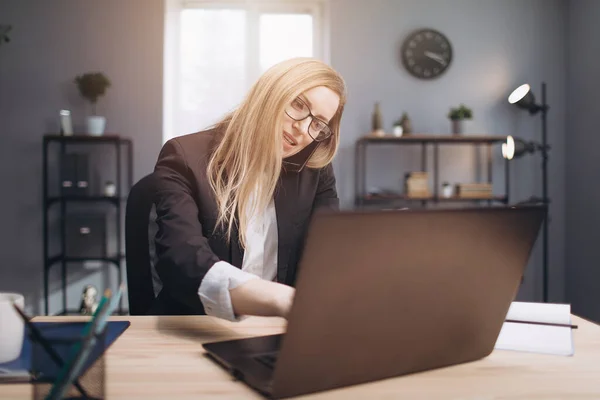 Жінка має телефонну розмову під час роботи на ноутбуці — стокове фото
