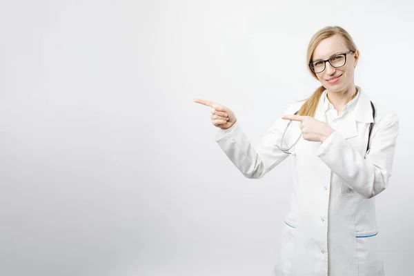 หมอผู้หญิงที่ยิ้มชี้ด้วยนิ้วมือเพื่อคัดลอกพื้นที่ — ภาพถ่ายสต็อก
