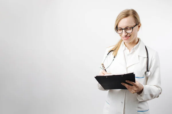 Улыбающаяся женщина-врач в очках, пишущая на планшете — стоковое фото