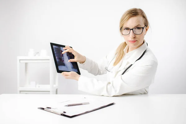 Женщина-врач показывает рентгеновский позвоночник на цифровом планшете — стоковое фото