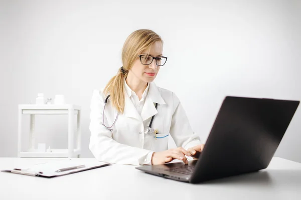 Mulher de uniforme médico trabalhando com laptop no escritório — Fotografia de Stock