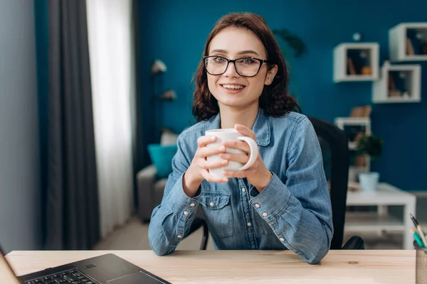 Smiling lady having coffee break while working on laptop