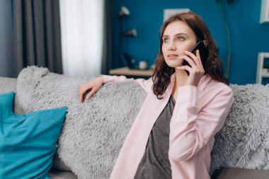 Hoş bir bayan akıllı telefonda rahat bir koltukta konuşuyor.