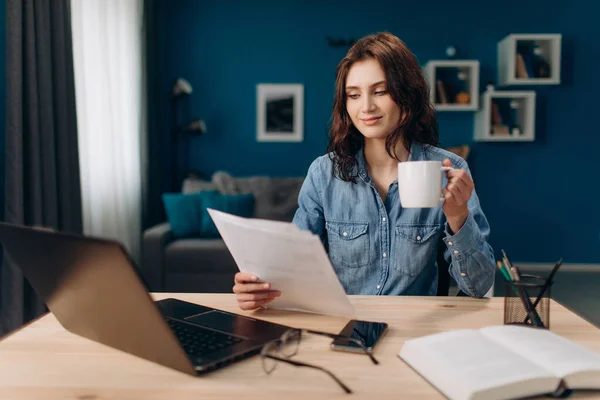 Ung flicka dricka kaffe och läsa dokument — Stockfoto