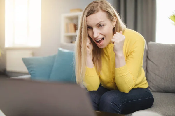 Mulher emocional olhando para a tela do computador no sofá — Fotografia de Stock