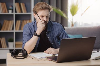 Uzaktan kumanda sırasında dizüstü bilgisayar kullanan düşünceli bir adam.