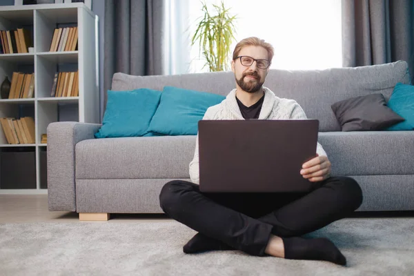 Homem feliz sentado no chão com laptop em casa — Fotografia de Stock