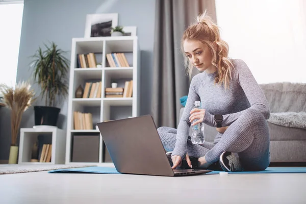 Chica joven en desgaste activo sentado en el suelo y el uso de la computadora portátil — Foto de Stock