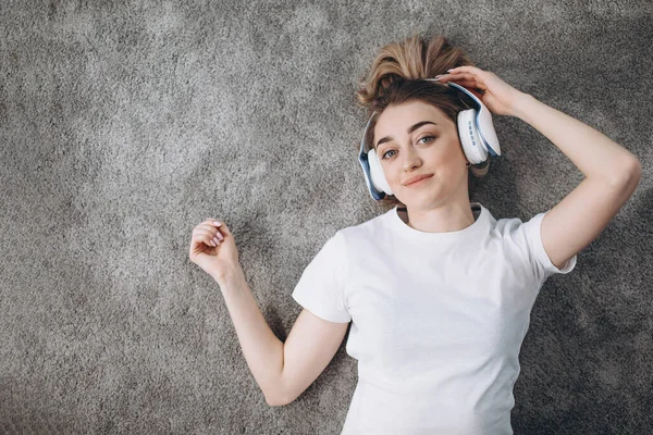 Vista superior de chica fitness relajante en la alfombra en los auriculares — Foto de Stock